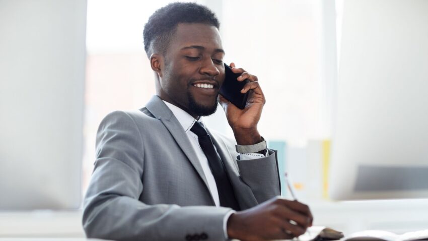 Un homme assis à son bureau, parlant au téléphone